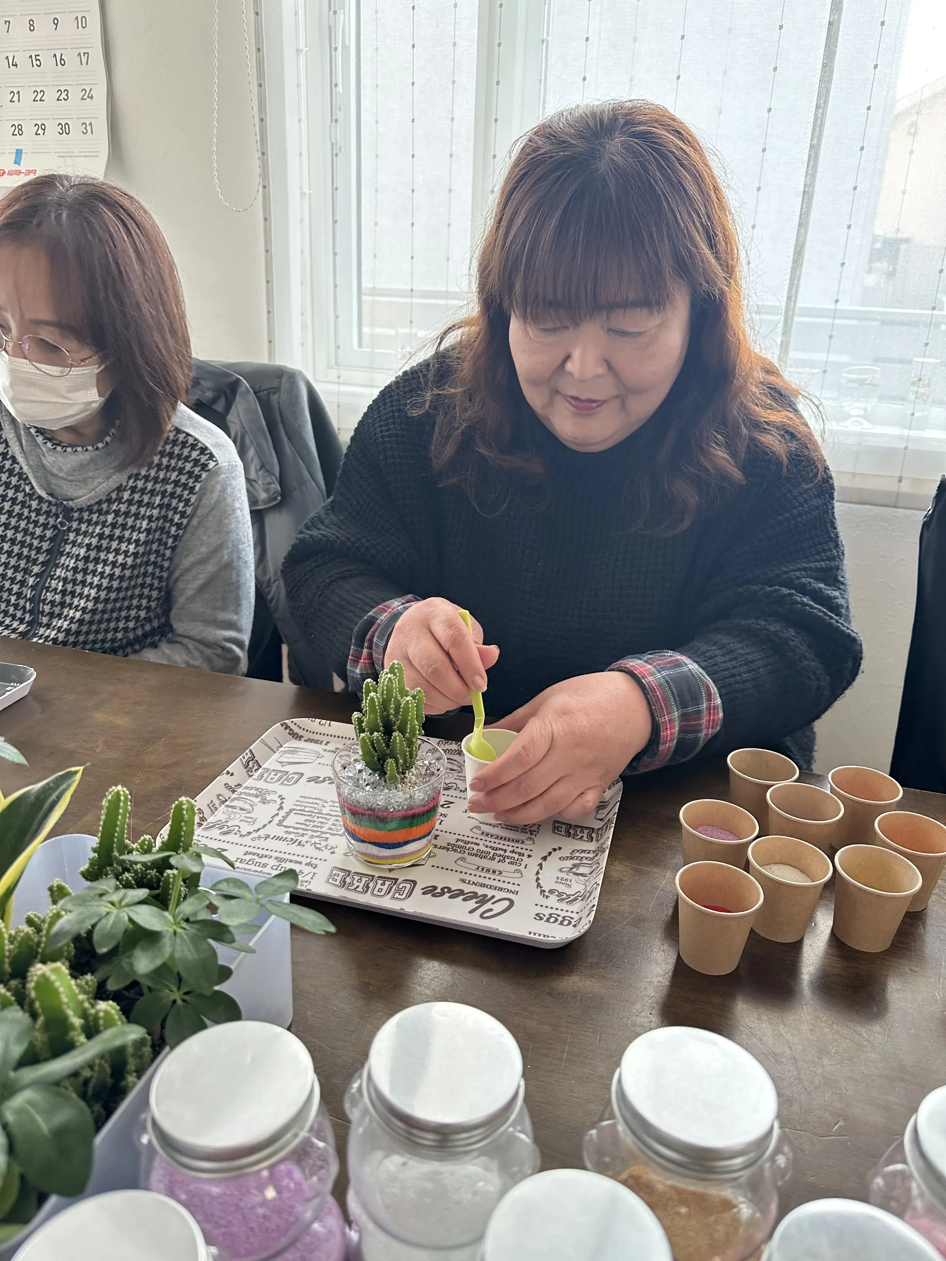 観葉植物を選んでサンドアートの鉢に植えている様子